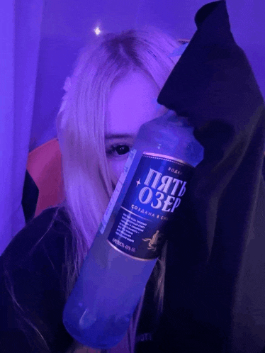 a girl is holding a bottle of five ozero vodka in front of her face