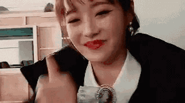 a woman in a black jacket and white shirt is holding a cup and smiling .