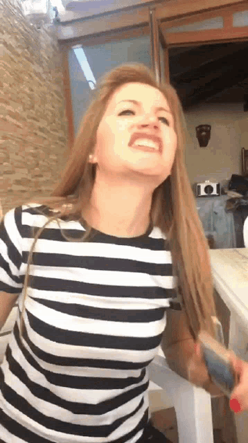 a woman in a black and white striped shirt is making a face