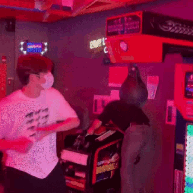 a man wearing a mask is playing a video game with a punching bag .