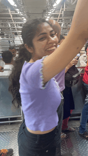 a woman in a purple shirt is smiling and holding her arm up in the air