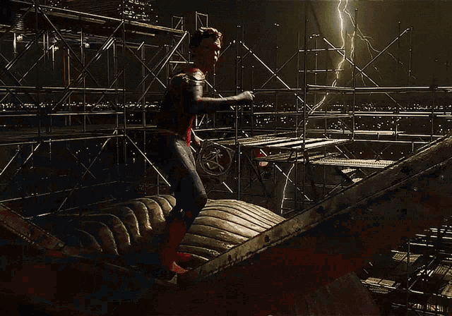 a man in a spiderman costume is standing on a ledge with a lightning bolt in the background