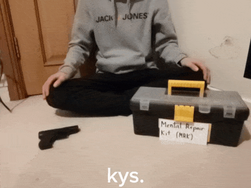 a man in a jack jones hoodie sits on the floor next to a toolbox and a gun