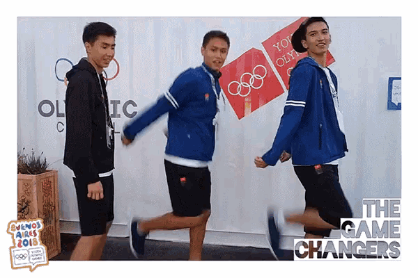 a group of young men are running in front of an olympic sign