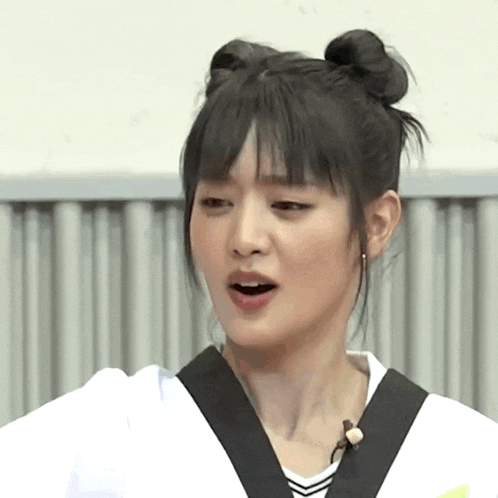 a woman with two buns in her hair is wearing a white shirt and black belt