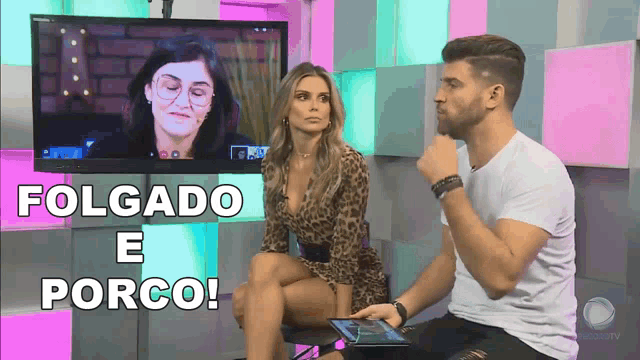 a man and a woman are sitting in front of a tv screen with the words folgado e porco