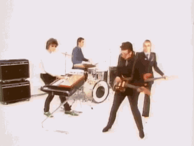 a group of men are playing guitars and drums in a room .
