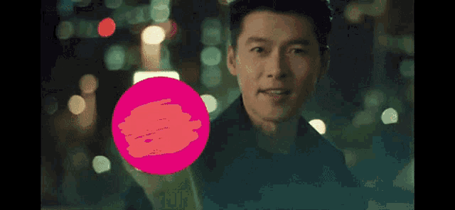 a man is standing in front of a pink circle and looking at the camera .