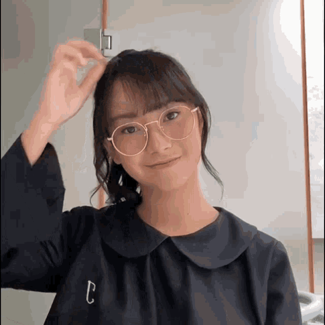 a girl wearing glasses and a black shirt with the letter c on the sleeve