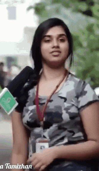 a woman wearing a camouflage shirt is holding a green microphone ..