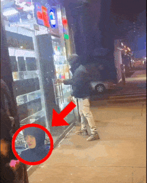 a man in a hoodie is standing outside of a store