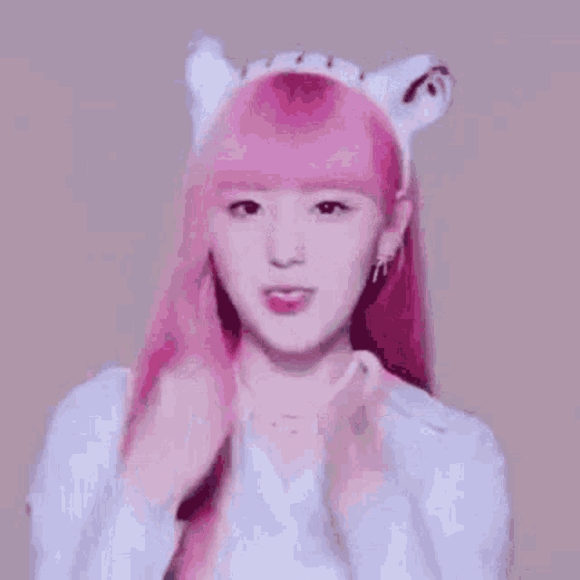 a girl with pink hair is wearing a cat ear headband .