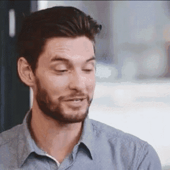 a man with a beard wearing a blue shirt is smiling .