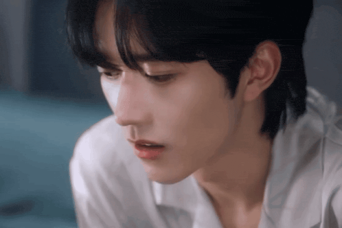 a close up of a young man 's face with a white shirt on