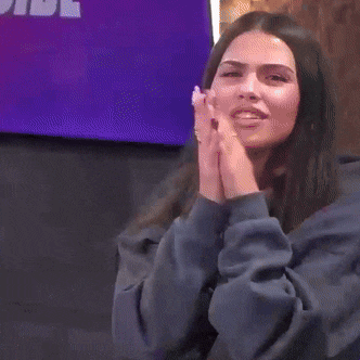 a woman blowing a kiss in front of a purple screen