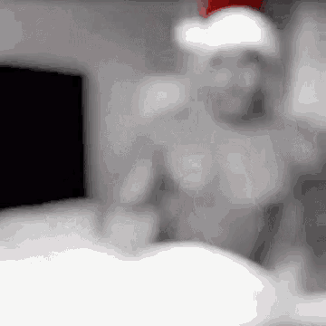 a blurred image of a shirtless man wearing a santa hat in a room .