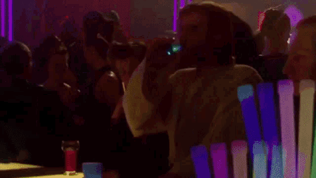 a man is standing in front of a row of glow sticks in a crowded room .