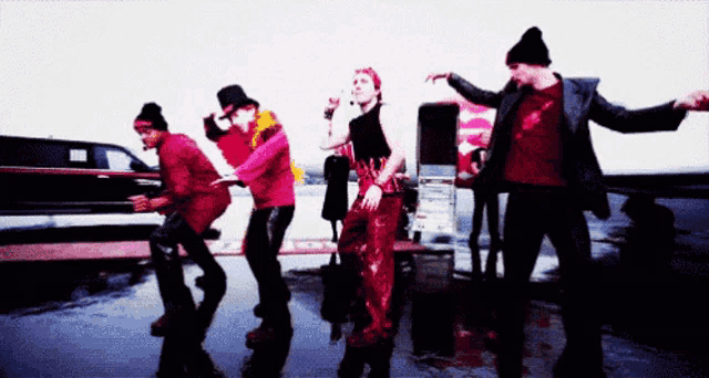 a group of people are dancing in front of a car that says ' ford ' on the side