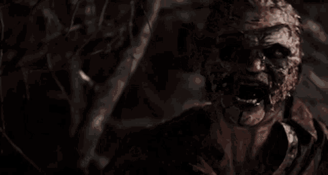 a man with a bloody face is standing in a dark forest