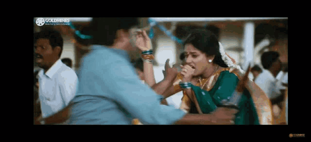 a man and a woman are dancing in a crowded room . the man is wearing a blue shirt .