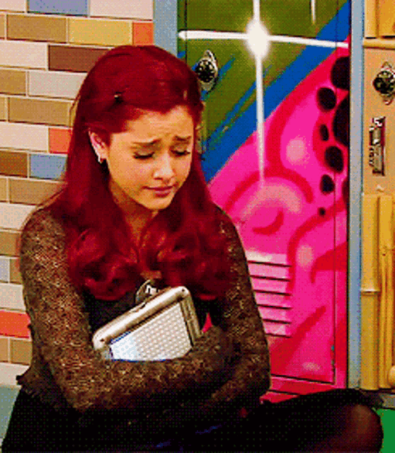 a girl with red hair is sitting in front of a colorful locker