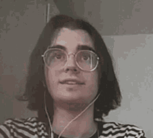 a woman wearing glasses and headphones is smiling and looking at the camera .