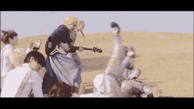 a group of people are playing a guitar in a field