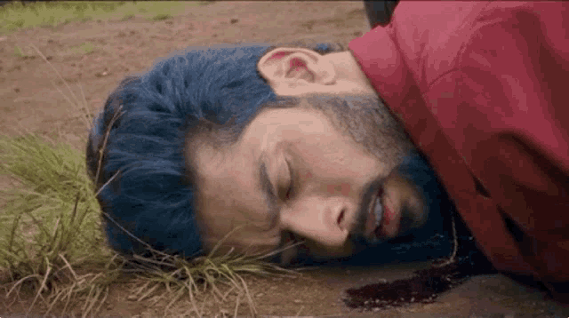 a man laying on the ground with blood on his face .