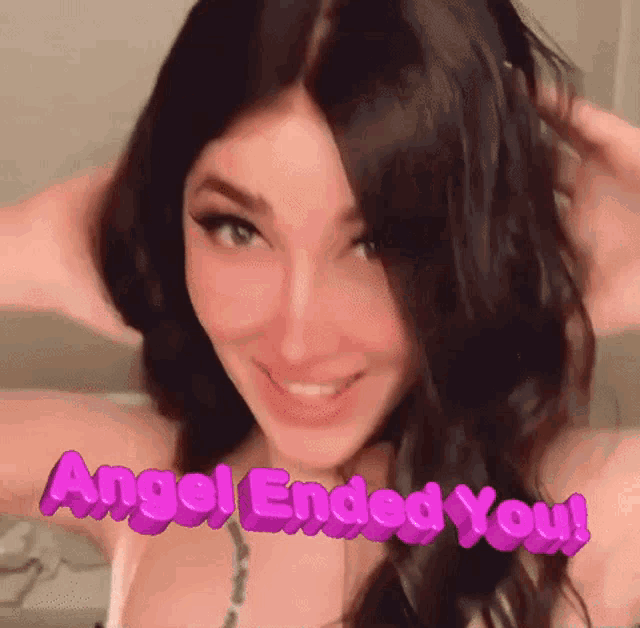 a woman is smiling and holding her hair in front of a sign that says angel ended you !