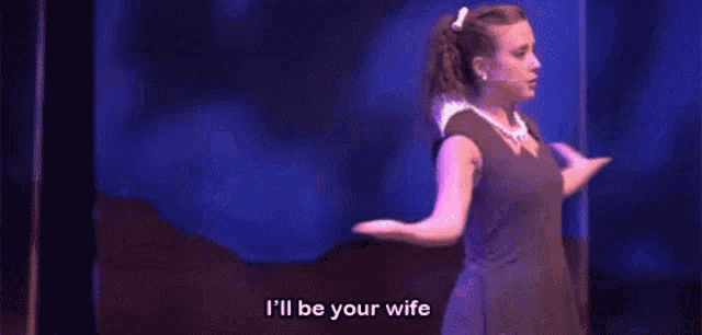 a woman is standing on a stage with her arms outstretched and says `` i 'll be your wife '' .