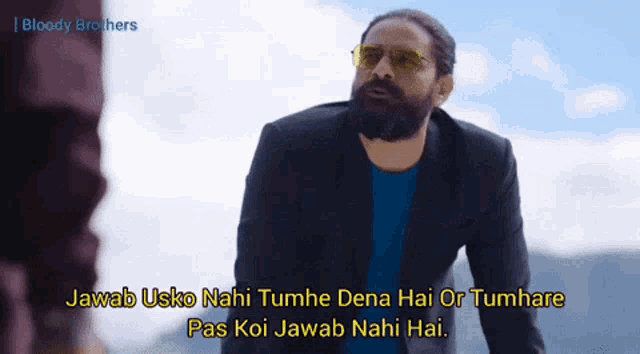 a man with a beard wearing sunglasses and a blue shirt says " bloody brothers " in the corner