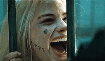 a woman with a tattoo on her face is behind bars .