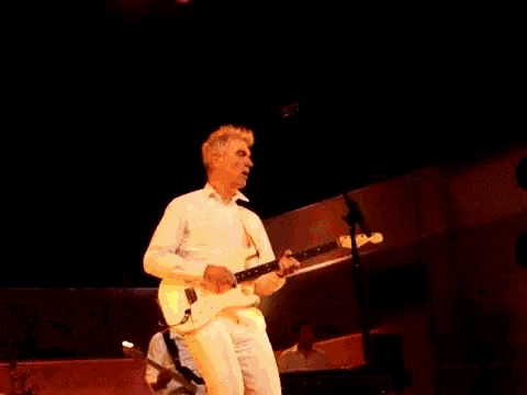 a man playing a guitar on a stage in front of a keyboard