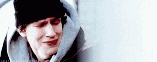 a close up of a man wearing a hat and a hoodie crying .