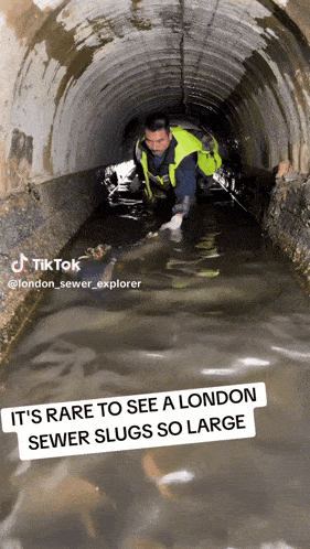 a man in a yellow vest is crawling through a sewer