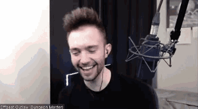 a man is smiling in front of a microphone in a studio .