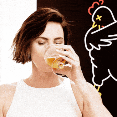 a woman is drinking a glass of beer in front of a drawing of a chicken