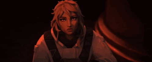 a woman with blonde hair is standing in a dark room with a red light behind her