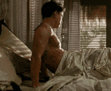 a shirtless man is sitting on a bed with his legs crossed