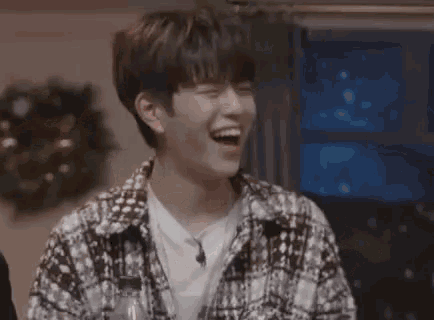 a young man is laughing while holding a bottle of water in a living room .