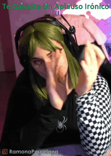 a woman with green hair wearing headphones and a black shirt with a spider on it