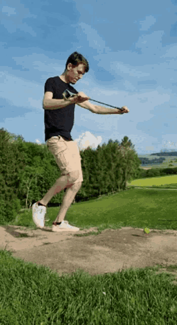 a man in a black shirt is jumping in the air while holding a slingshot