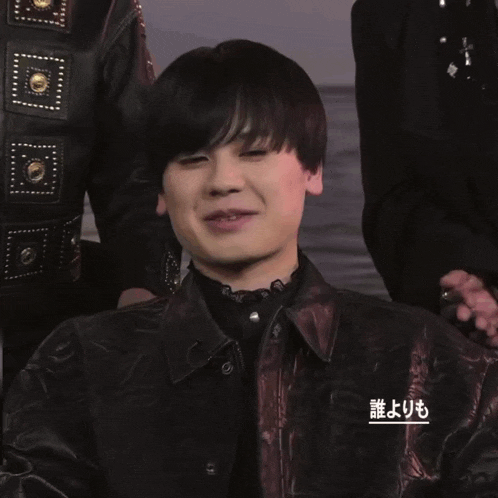 a person making a heart shape with their hands in front of a sign that says ' 誰 より も ' on it
