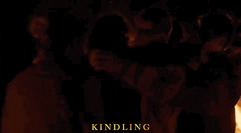 a group of people standing in front of a fire with kindling written in gold