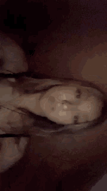 a woman is taking a selfie in a dark room while wearing a black bra and a necklace .