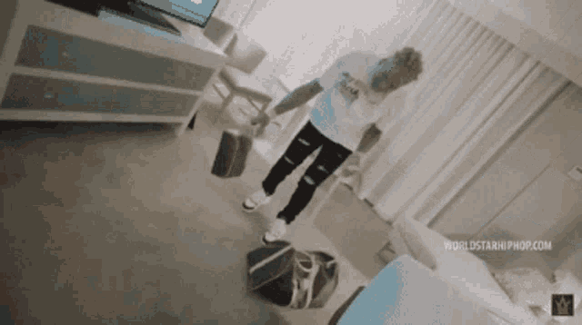 a man in a white shirt is standing in a hotel room holding a purse