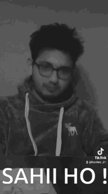 a black and white photo of a man wearing glasses and a sweatshirt that says sahi ho