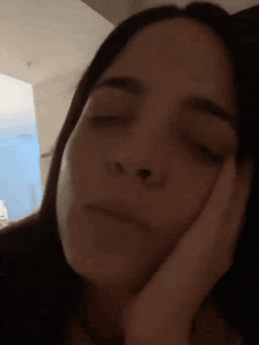 a close up of a woman 's face with her hand on her face