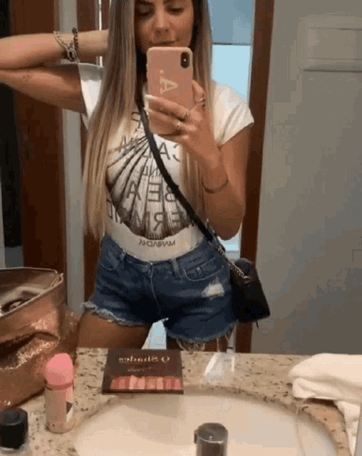 a woman is taking a picture of herself in a bathroom mirror with a phone that has the letter a on it