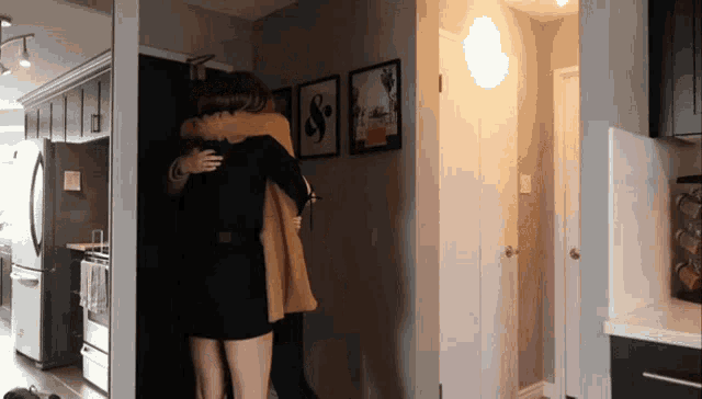 a couple hugging in a hallway with a s on the wall behind them